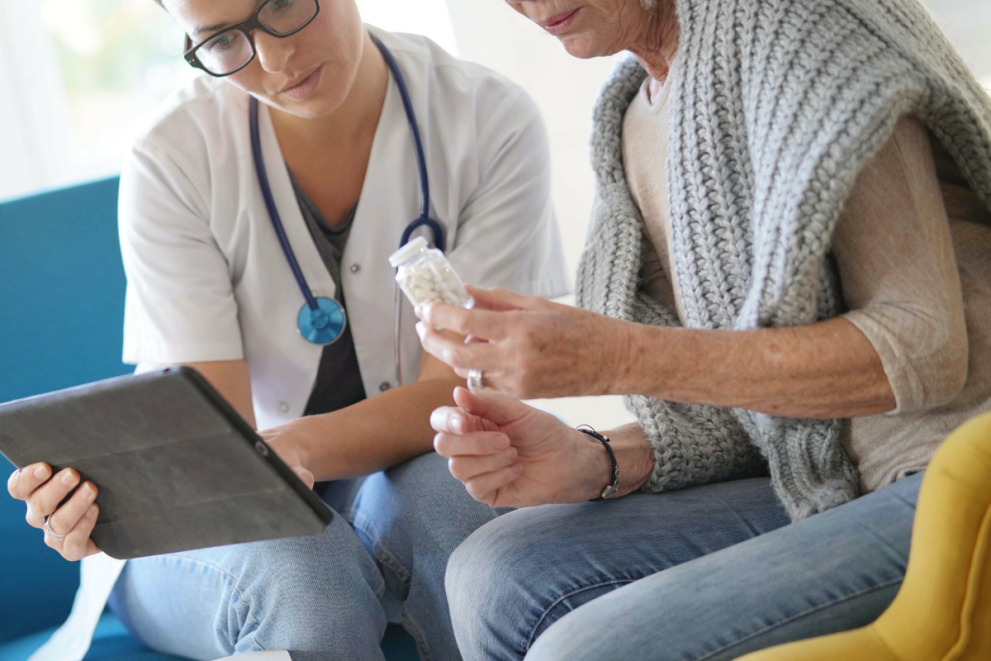 Doctor showing medical results on her tablet to a senior patient holding her medicine