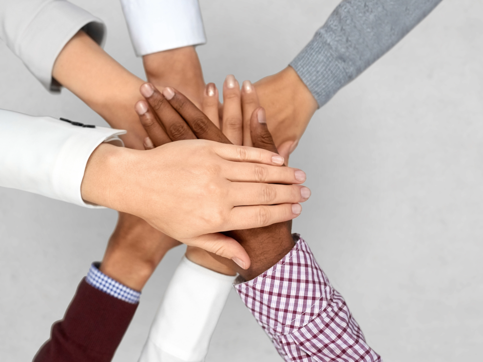 A Diverse team putting their hands together, representing teamwork.