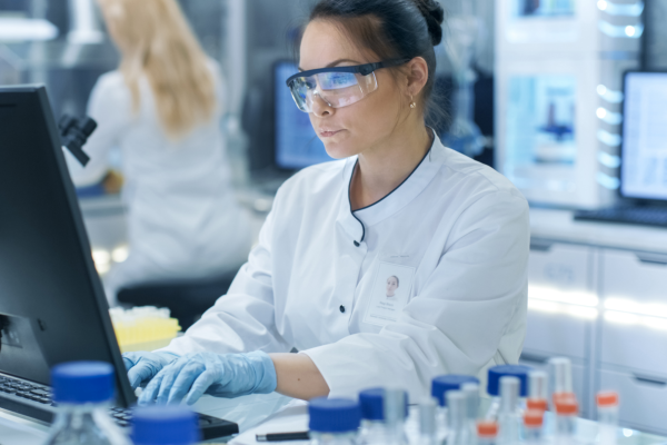 Female medical research scientist working in a modern laboratory and typing information obtained from new experimental drug trial